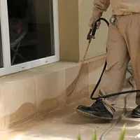 General pest control technician spraying exterior perimeter around a home in {city}, {state}